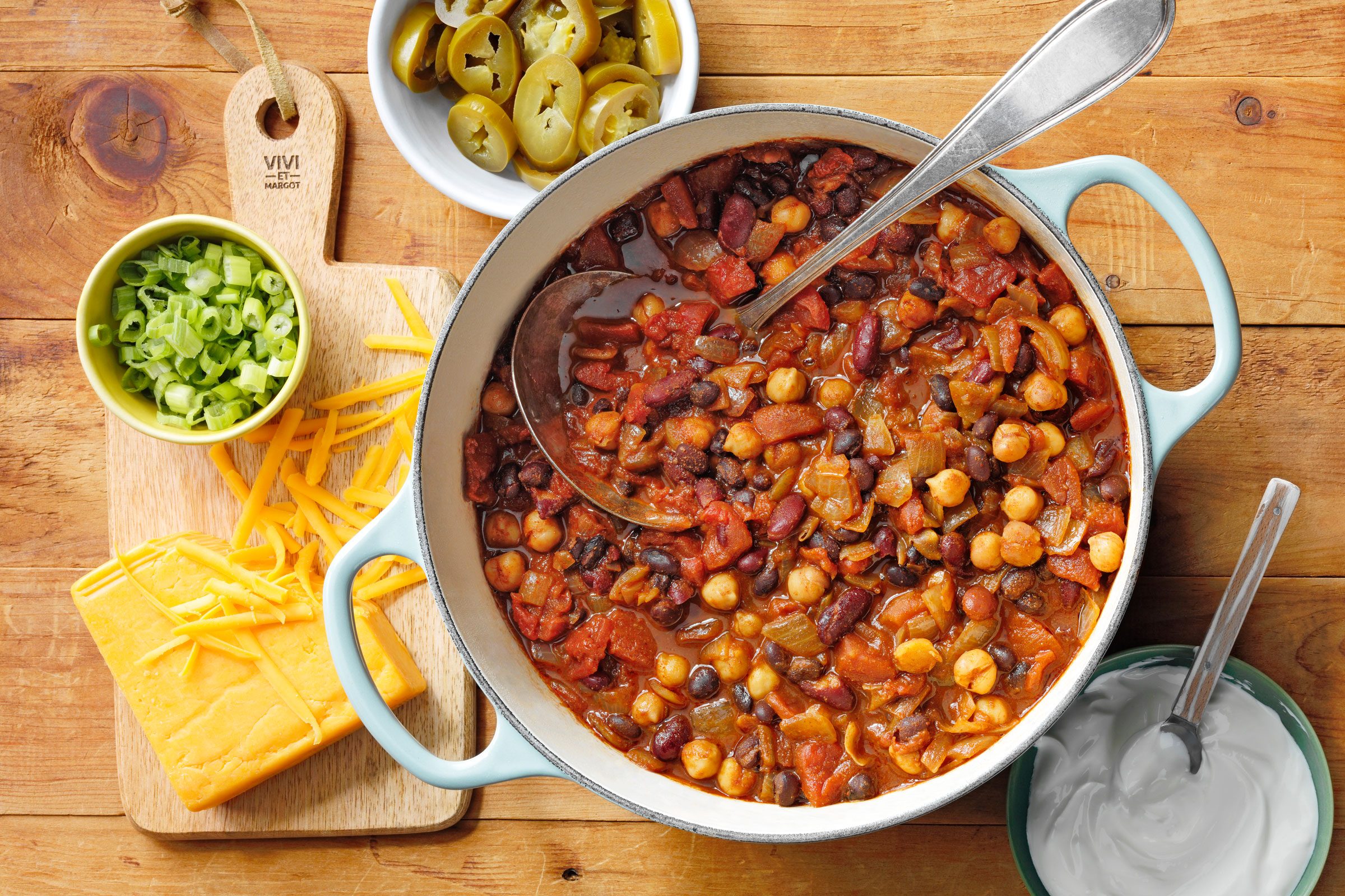 chili in a pot next to cheese, sour cream, jalepenos