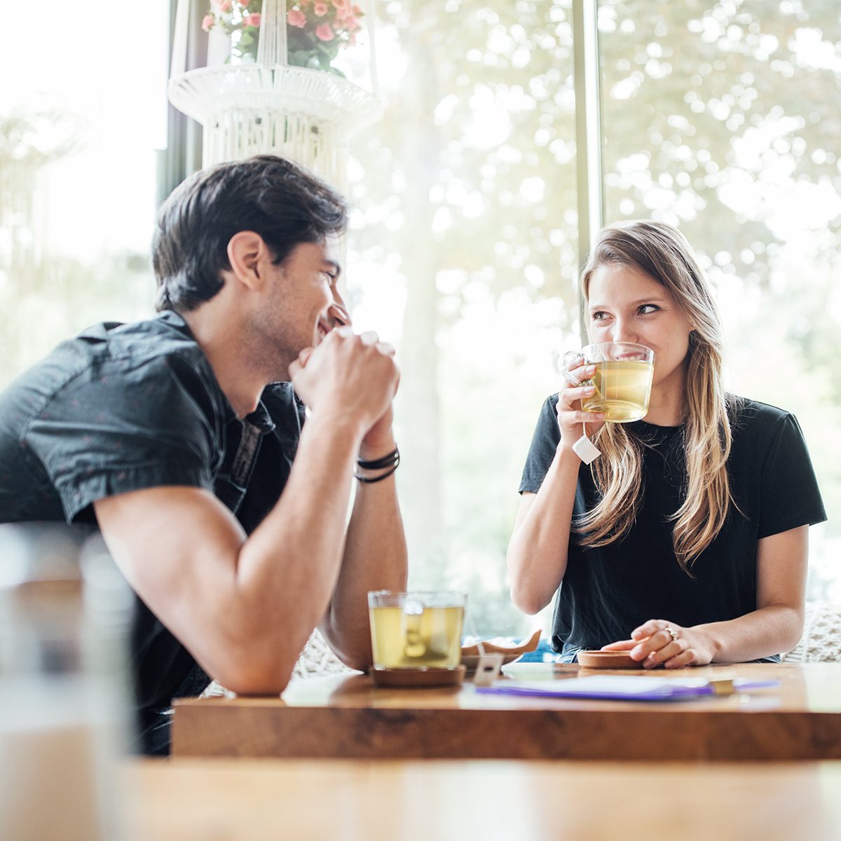 Young couple in love at cafe looking at each other and smiling. Woman drinking green tea and looking at her boyfriend.
