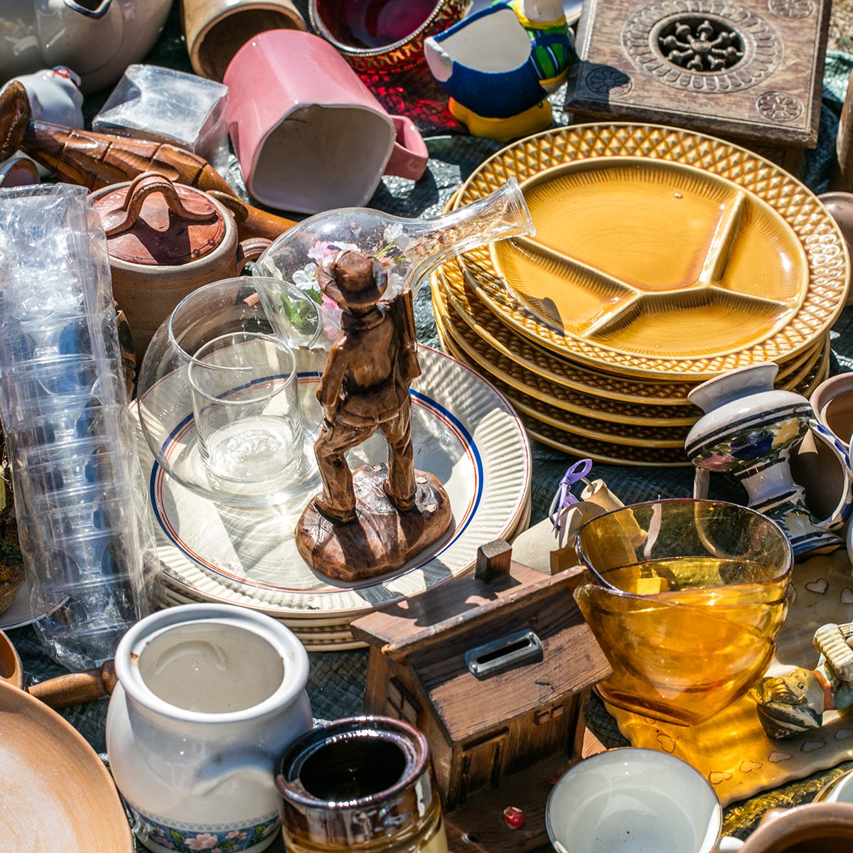 pile of household things, various dishes and decorative objects at boot sale for second hand, recycling or over-consumption society at outdoor welfare