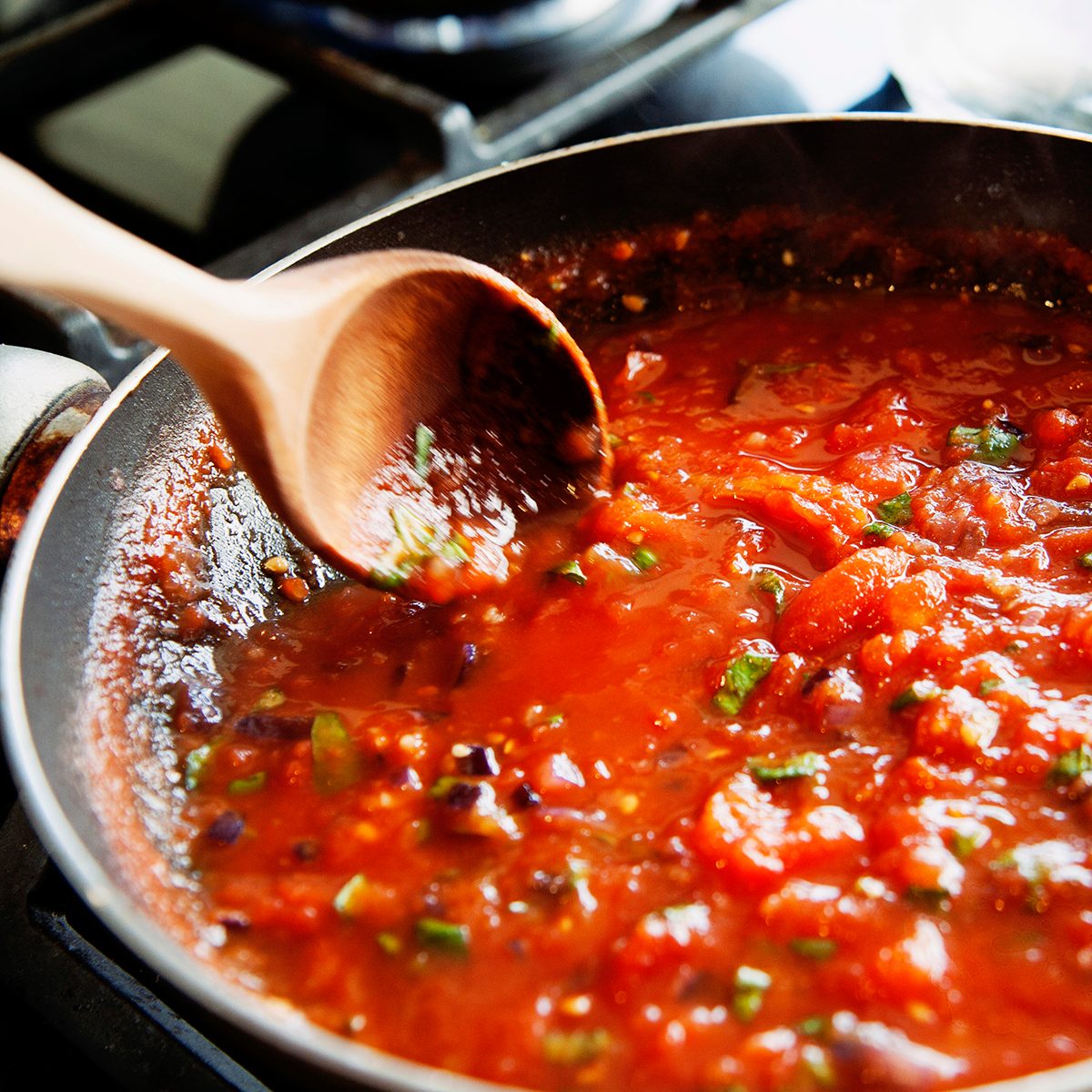 Vilnius, Lithuania - June 17, 2011: preparing of a homemade tomato sauce in a frying pan from fresh tomatoes.