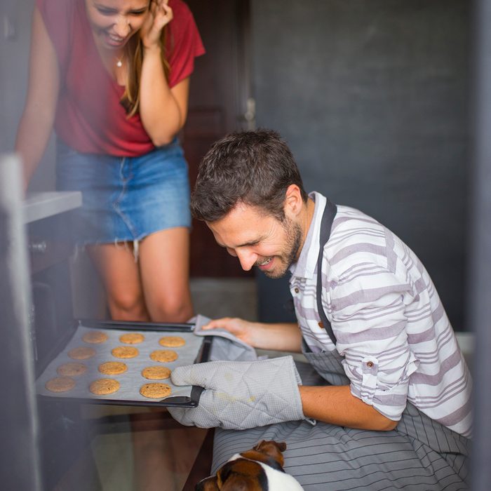 Young man checking food in oven low angle view