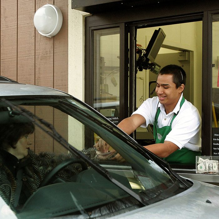 WHEELING, IL - DECEMBER 28: Starbucks worker Freddie Arteaga assists a customer with her drink order at a Starbucks drive-thru December 28, 2005 in Wheeling, Illinois. Starbucks is investing in the drive-thru market for coffee drinkers on the go. (Photo by Tim Boyle/Getty Images)