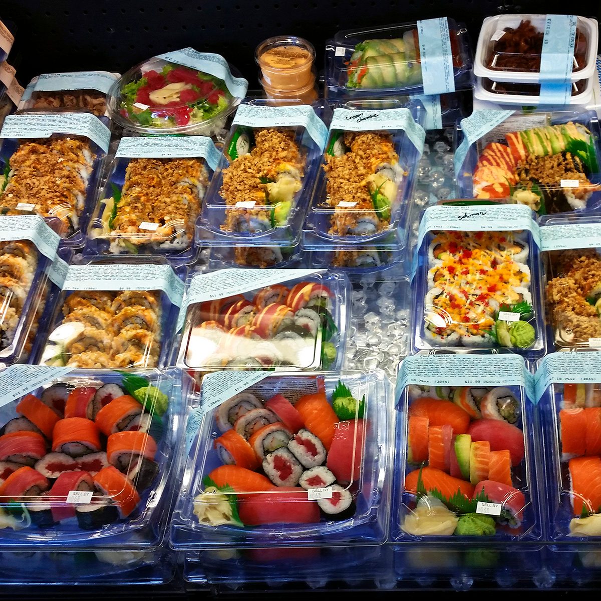 Supermarket display of assorted sushi items.
