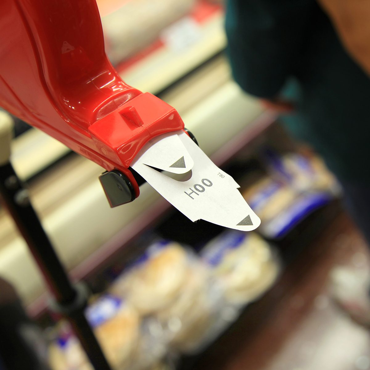 A customer is standing next to a ticket number dispenser at a grocery store, meat section.