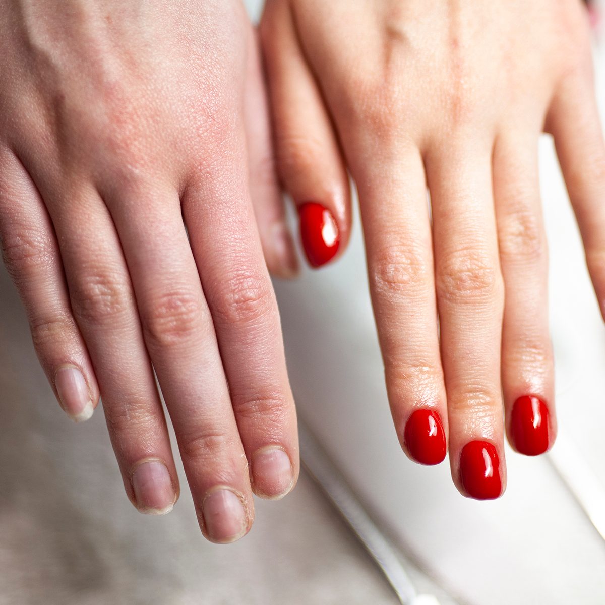 Woman filing nails using a nail file while doing her own nails.