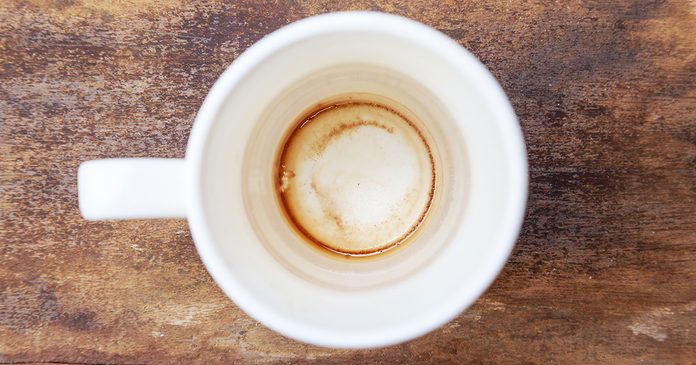 Cup of coffee drying mark in white cup on old wooden background crop