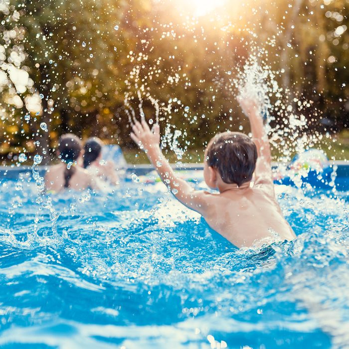 Photo of Three Caucasian happy children playing and splashing on the swimming pool at the day time. Concept of friendly family.