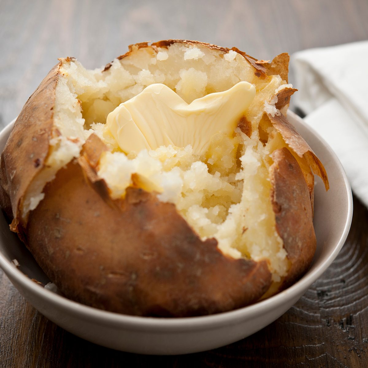Baked potato with melting butter, horizontal.