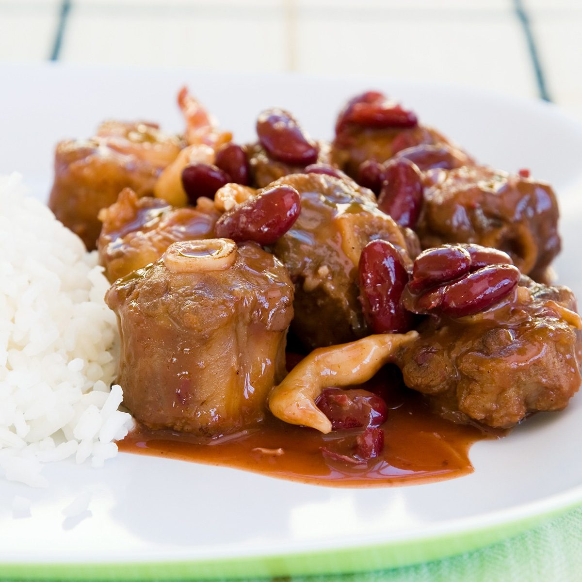 traditional jamaican foods Caribbean style curried Oxtail stew served with rice mixed with red kidney beans. Dish accompanied with vegetable salad. Shallow DOF.