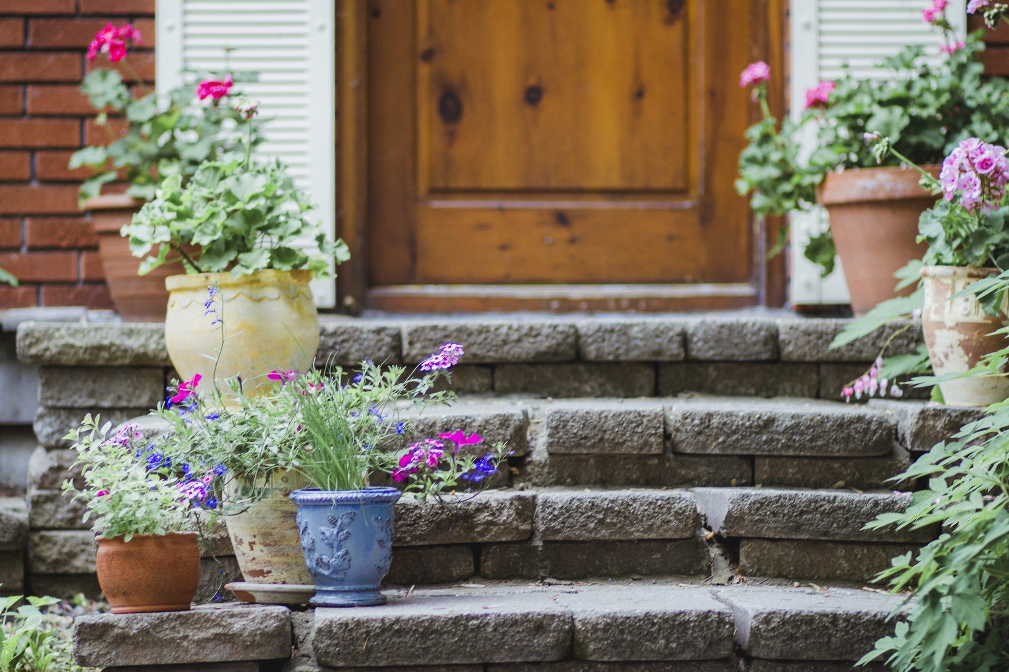 Potted Plants With Flowers On The Steps Of A House Porch