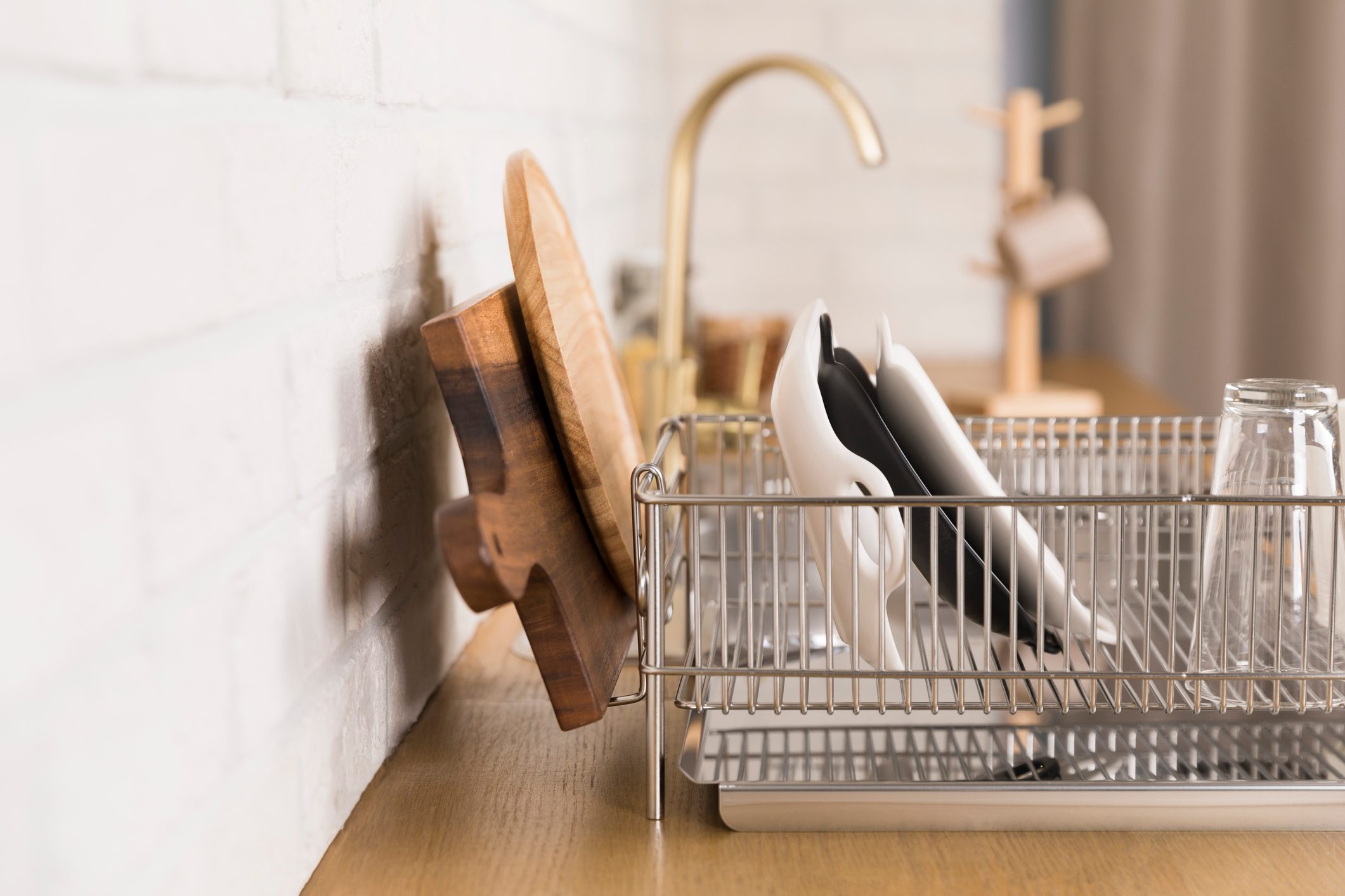 dishes and wooden cutting boards drying on dish rack next to the sink