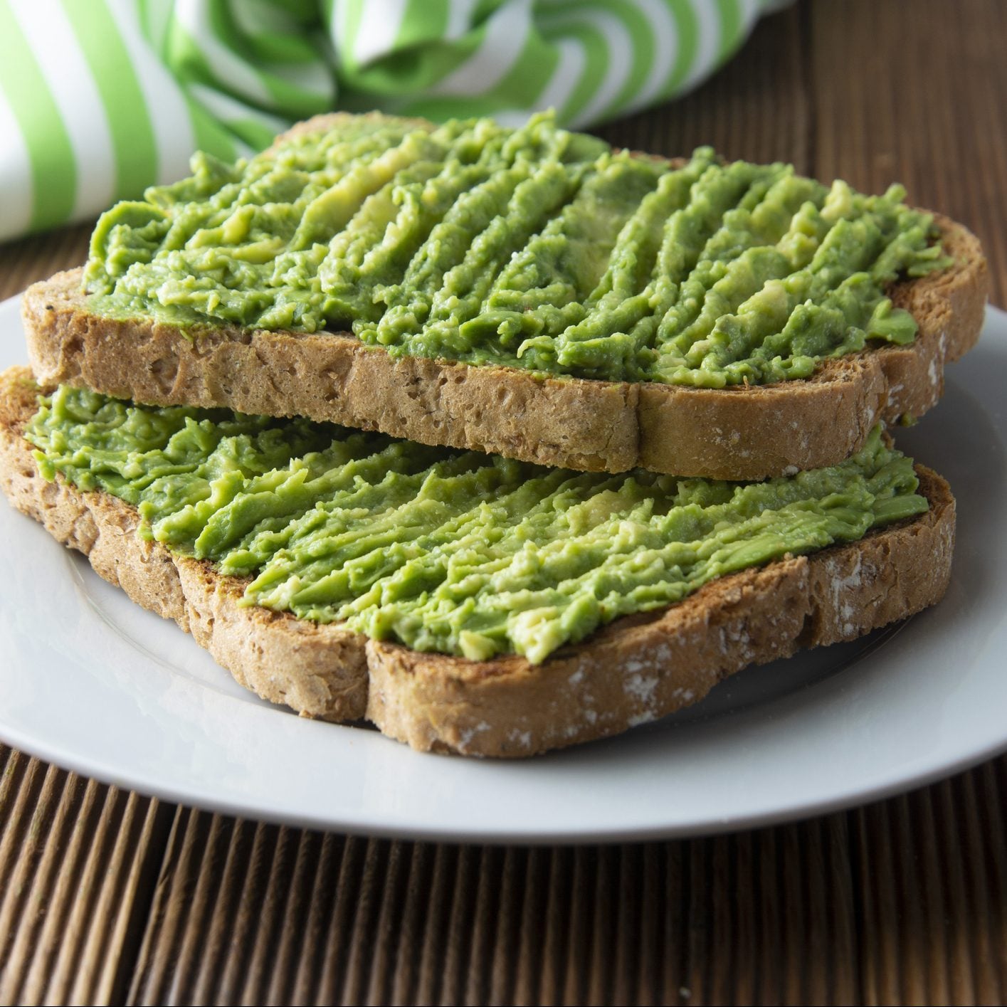 two pieces of avocado toast on a white plate