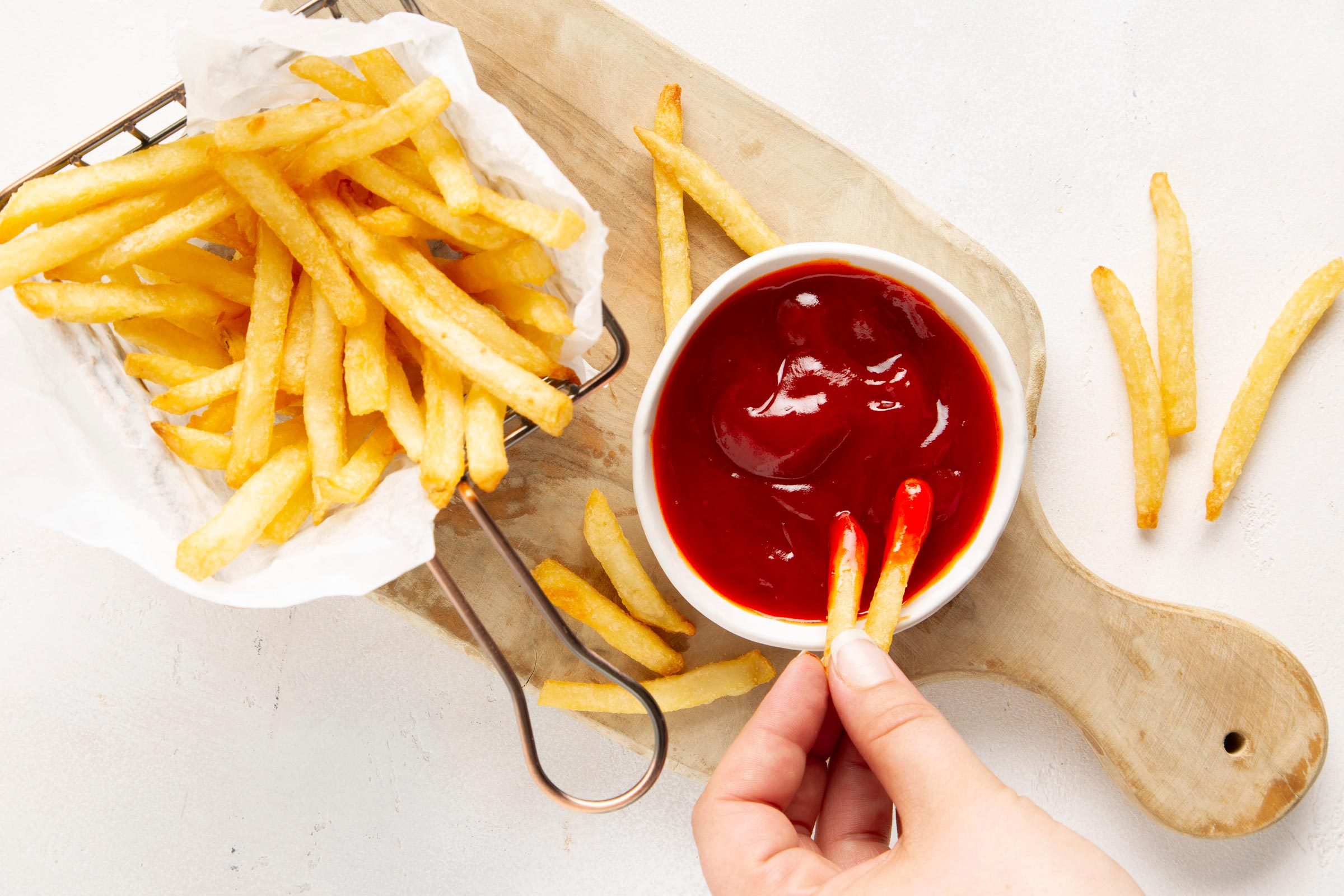 hand dipping french fries in banana ketchup