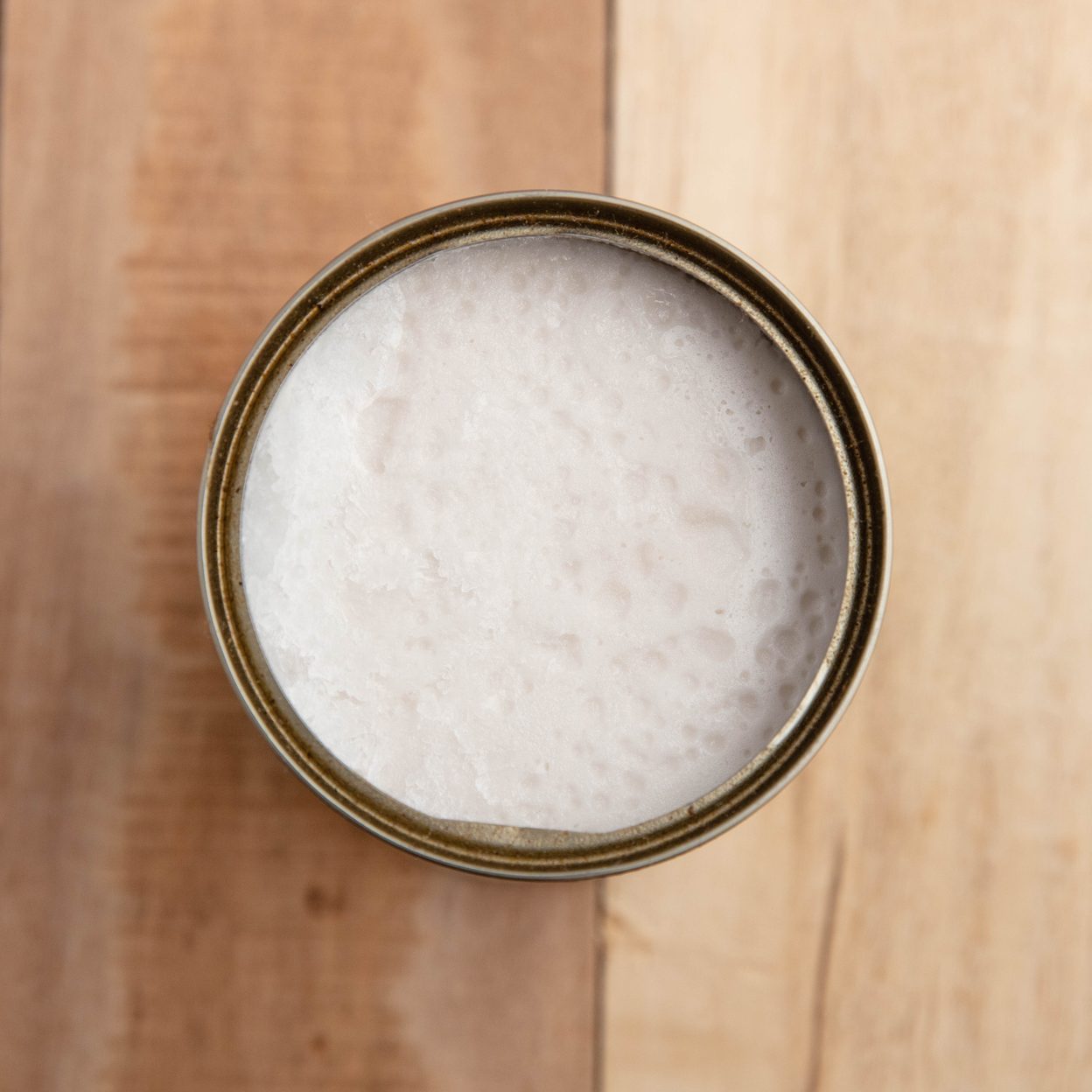 opened canned Coconut milk overhead on wooden table
