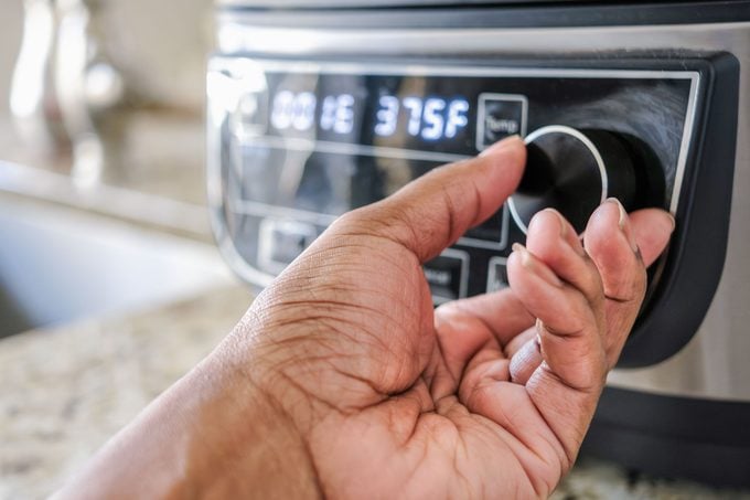 Woman Adjusting Temperature On Air Fryer