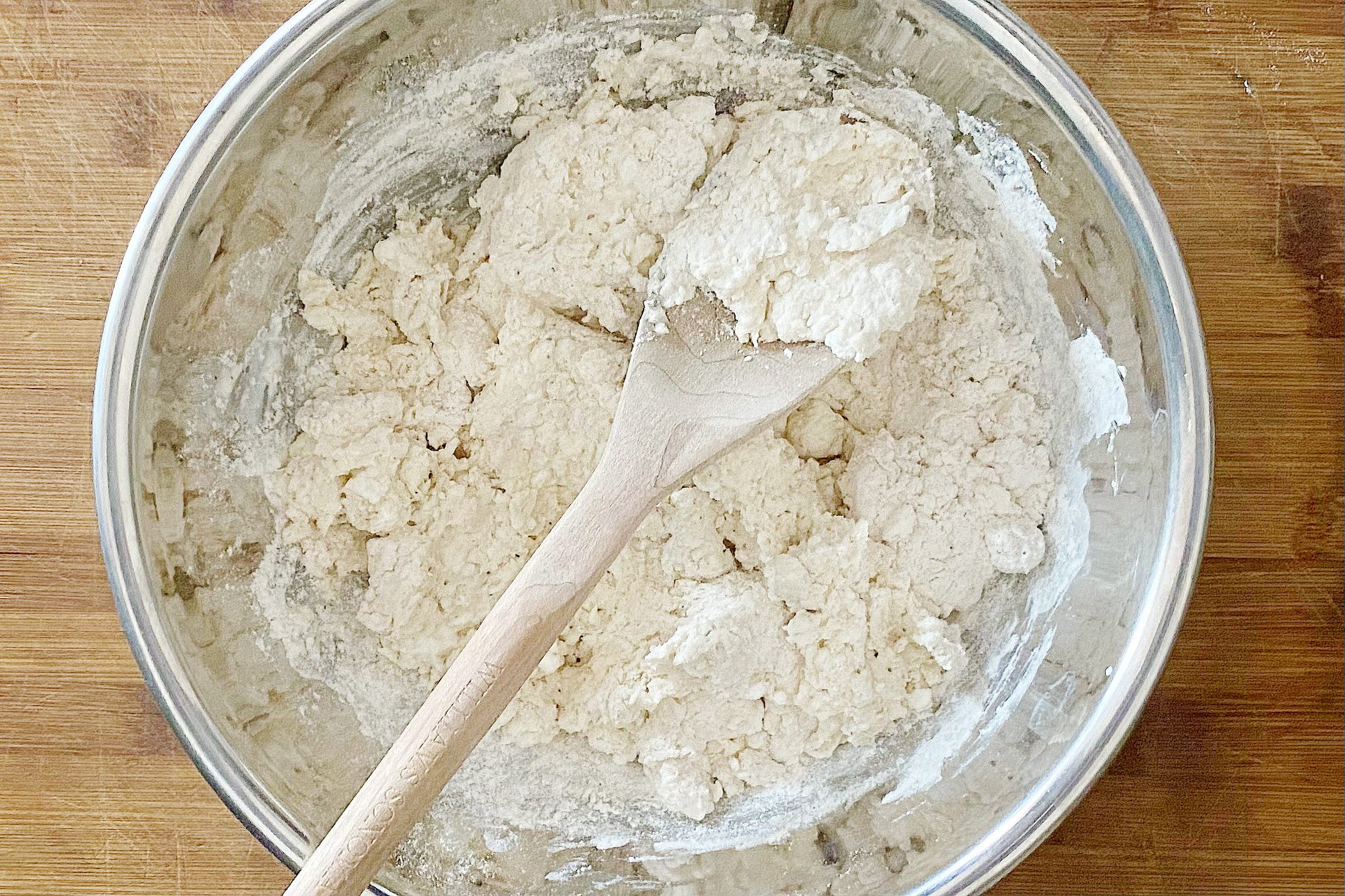 mixing dough with a wooden spoon i na large glass bowl