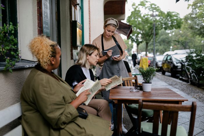 Waitress Taking Order From Customers Sitting Outside Restaurant