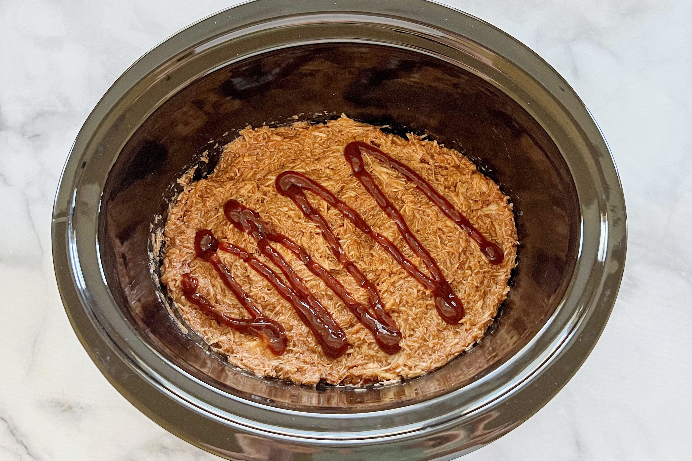 cooked shredded chicken in a crock pot with bbq sauce