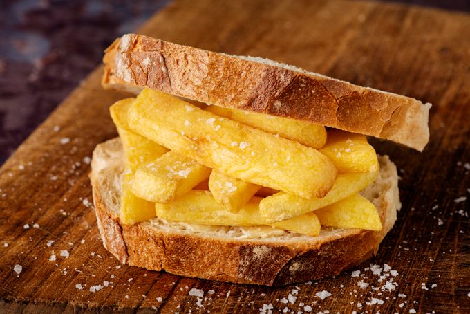 English Dish "Chip Butty" with french fries on buttered bread on a wooden countertop