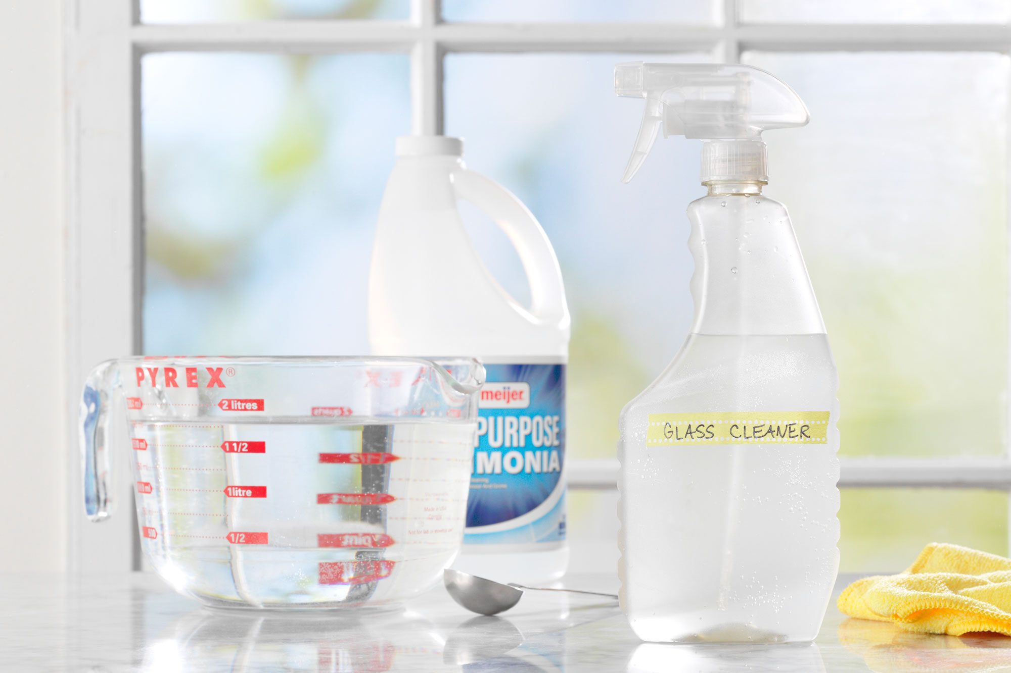 homemade Glass Cleaner ingredients on a marble surface in front of a window