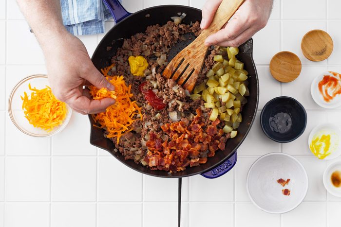 top view of a skillet with ingredients for cheese burger egg rolls