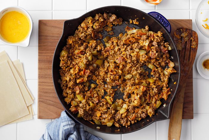 top view of a skillet with cheeseburger egg roll filling