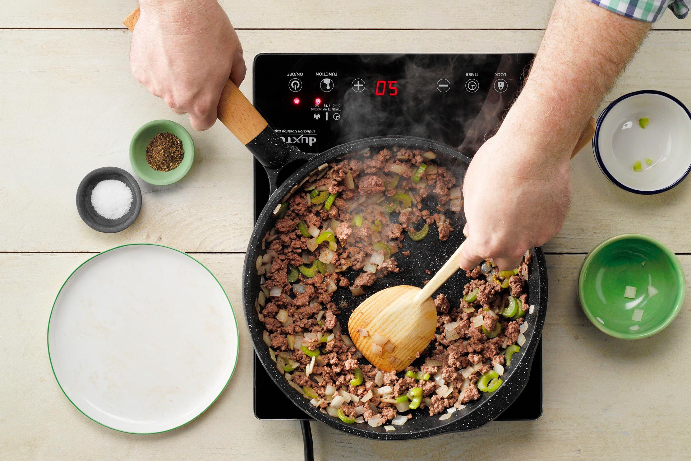 top view of beef cooking In a skillet with onions and peppers