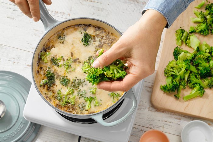 Pot With Hand Dropping In Broccoli