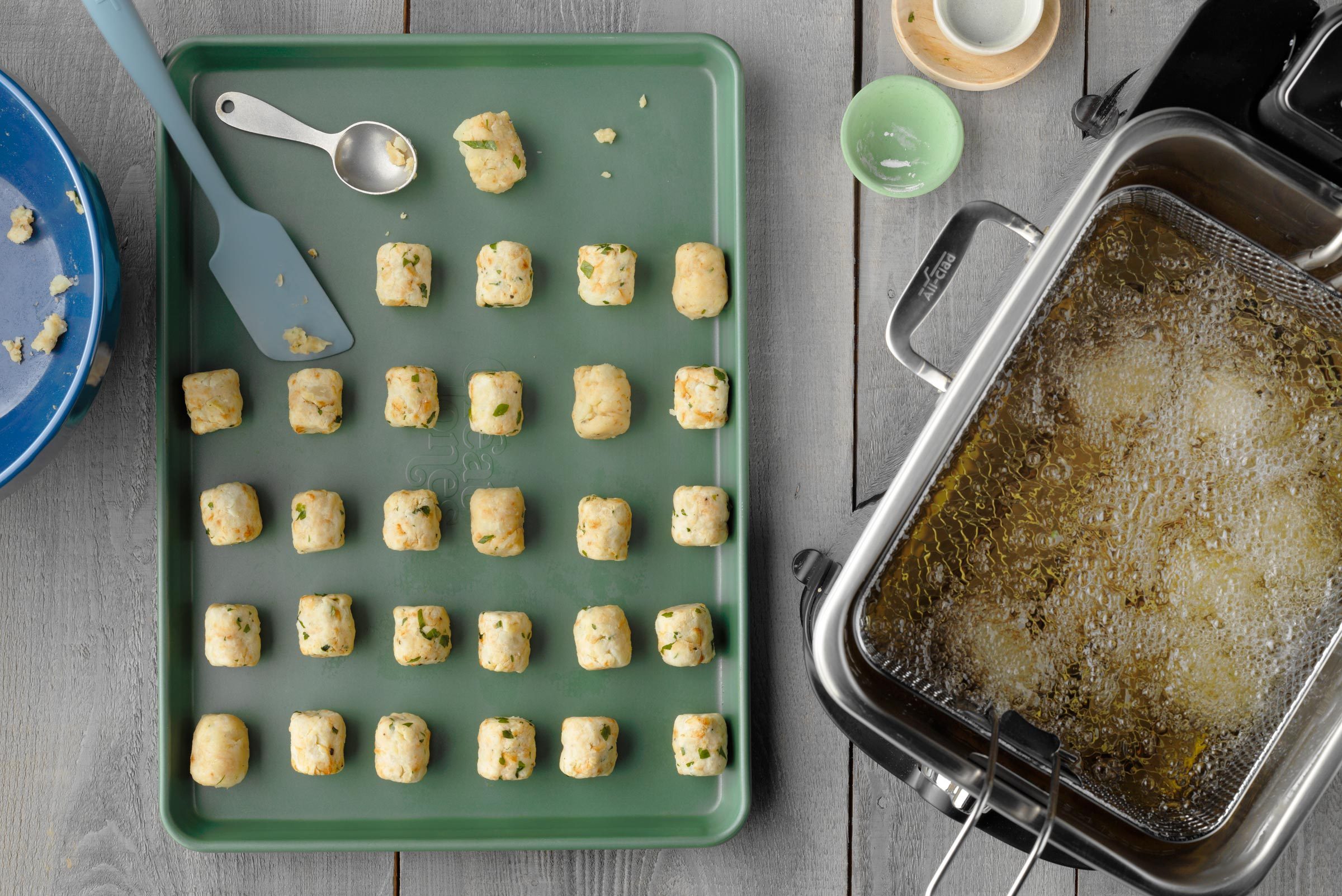 tater tots arranged on a baking sheet before being fried