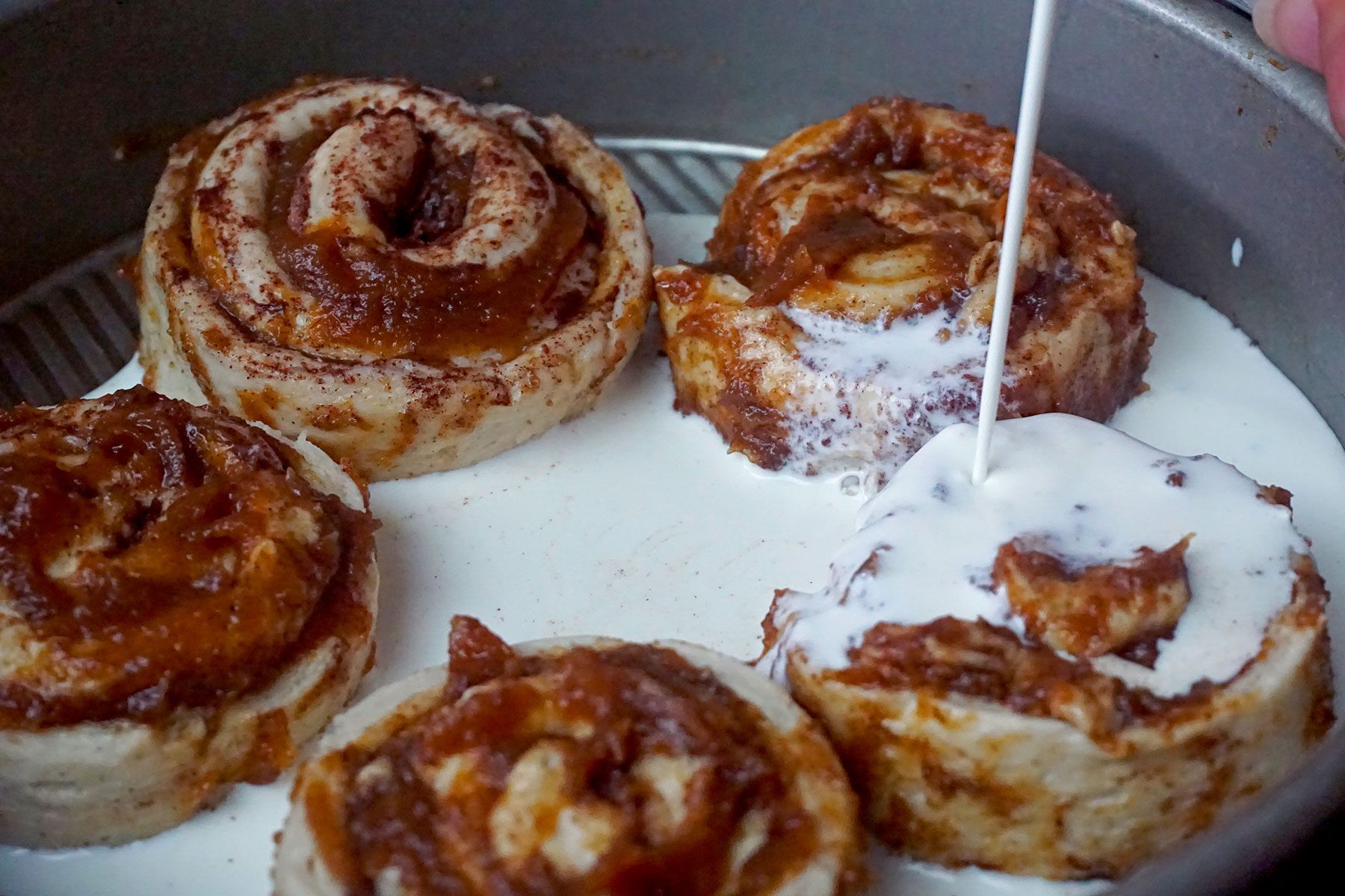 Pouring cream on cinnamon rolls