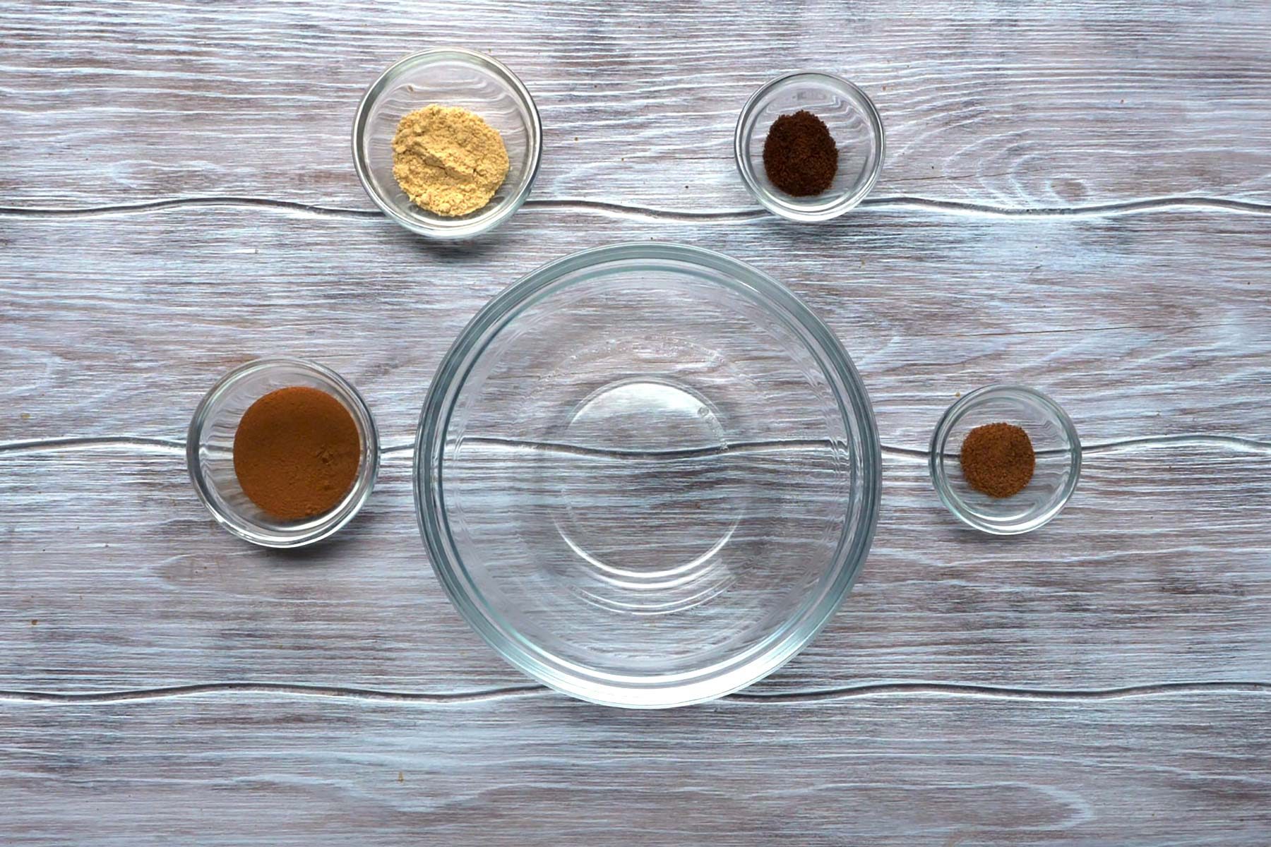 Spices in small bowls with an empty large bowl in center