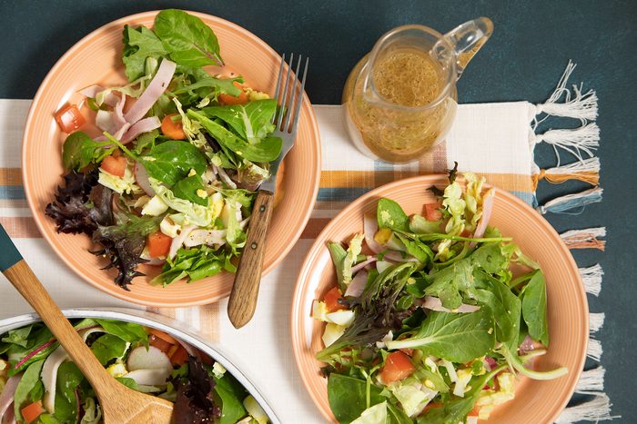 A bowl of salad with chicken, radishes, and carrots.