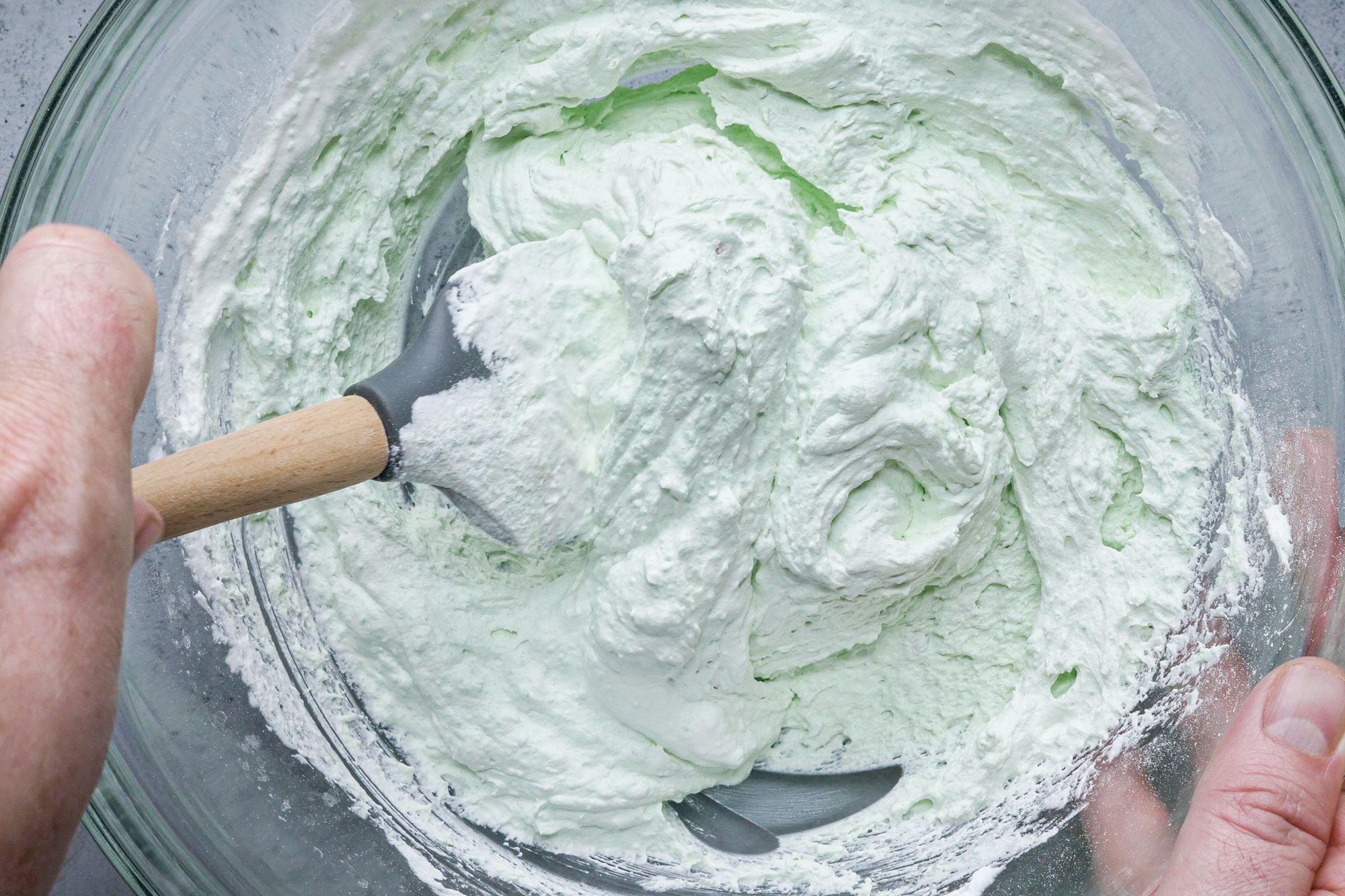 combining whipped ingredients for Pistachio Mallow Salad in a glass bowl