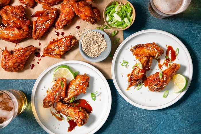 Plates of teriyaki chicken wings and beer on a table