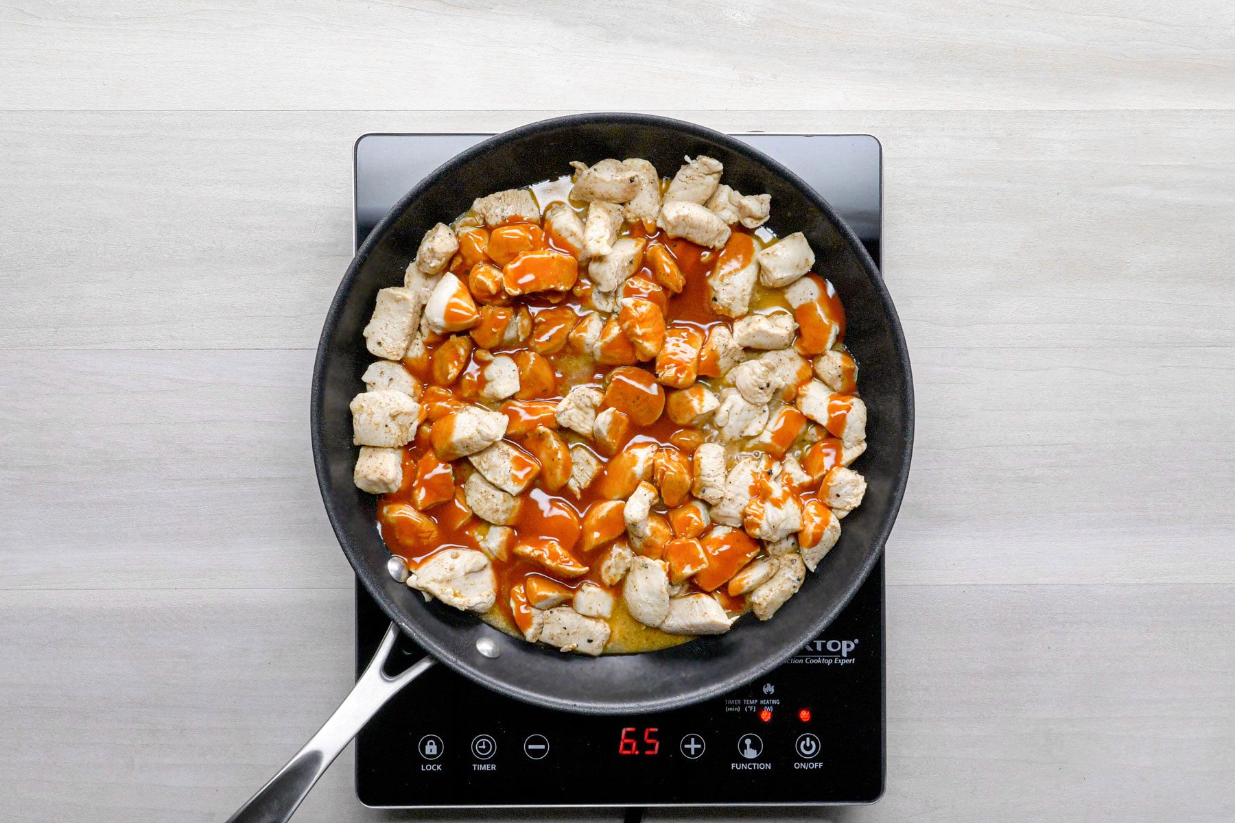 Chicken pieces with Buffalo wing sauce cooked in a pan