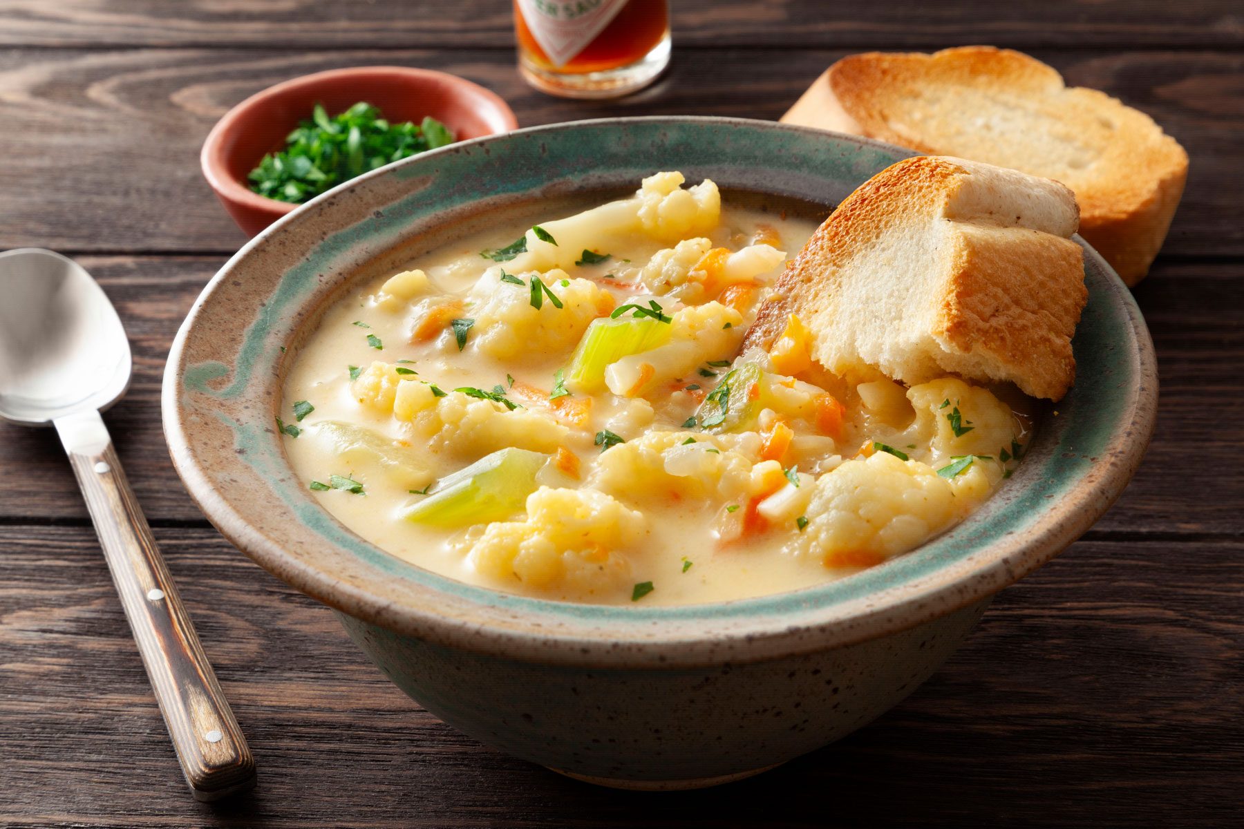 Cauliflower Soup served in a plate with bead on a wooden table