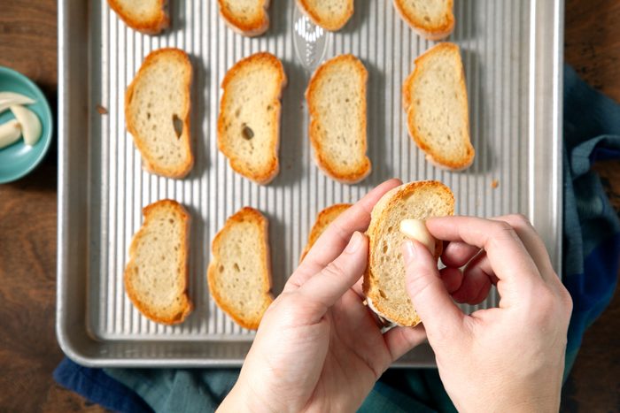 Rubbing the toasts with the halved garlic