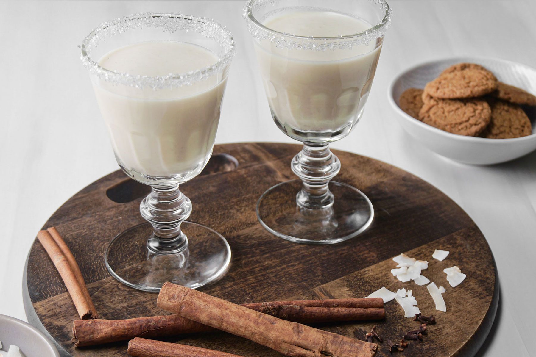 Two galsses of Coquito drink served on a wooden tray