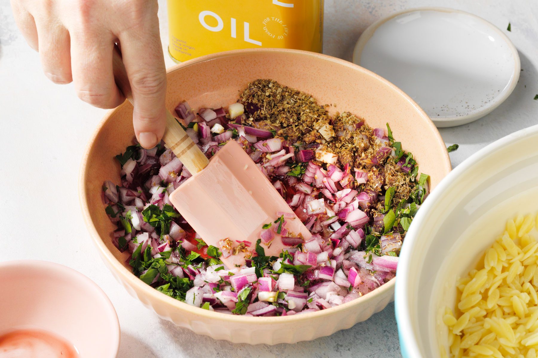 Combining the onion, parsley, vinegar, oregano in a large bowl using a spatula