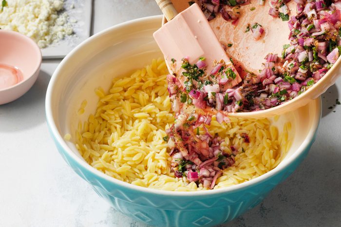 Combining the onion mixture in orzo using a spatula
