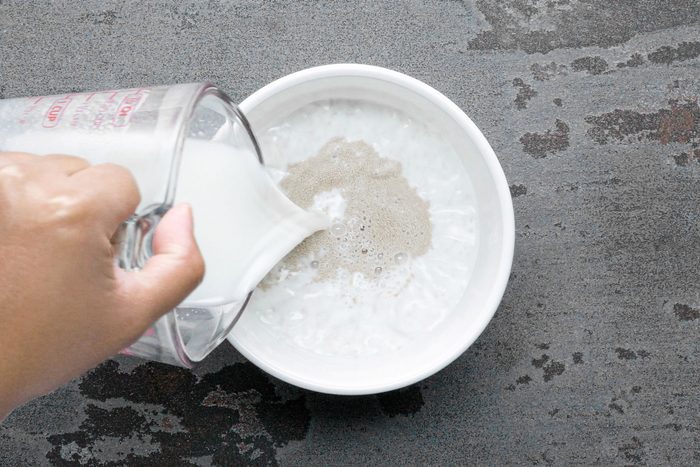 a person pouring warm milk into a large bowl