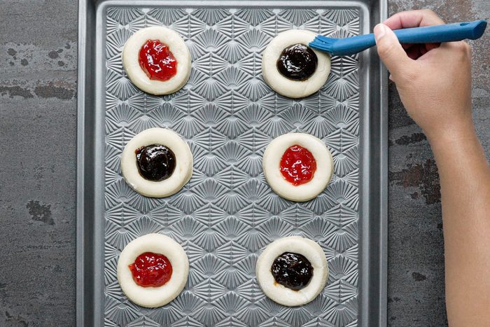 brushing raw Kolaches placed on a baking tray