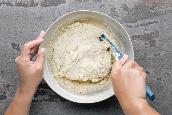 a person folding dough in a large bowl