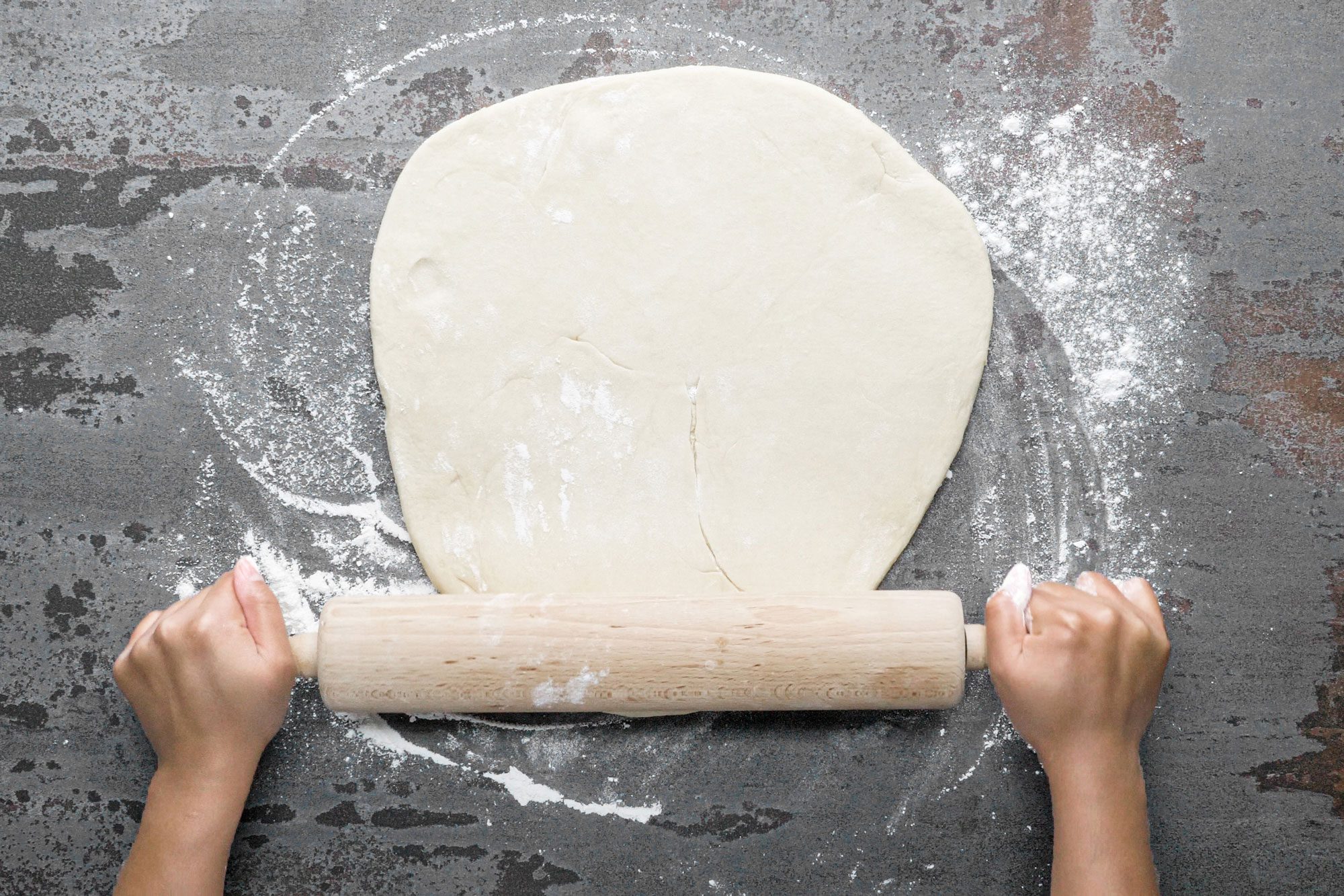 a person rolling dough using a rolling pin