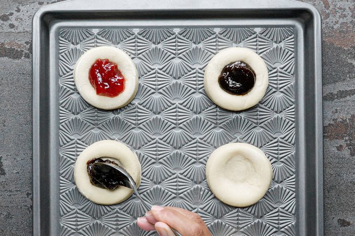 adding tablespoon of jelly to small dough pieces