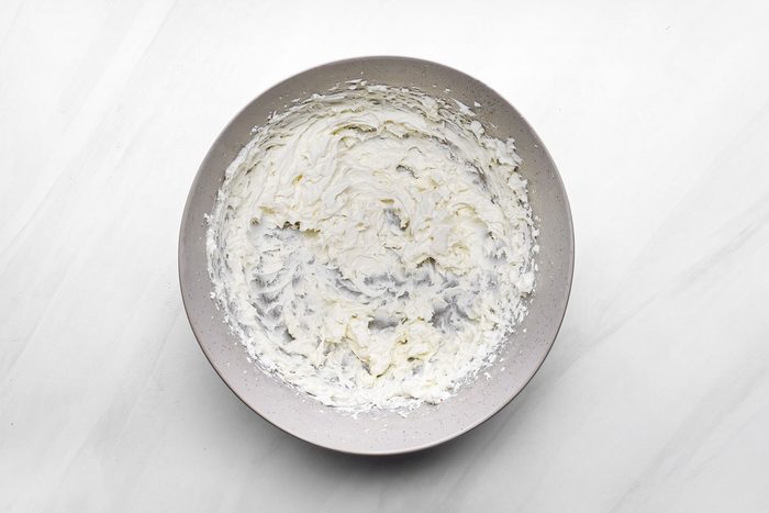 beaten cream cheese in a large bowl on marble surface