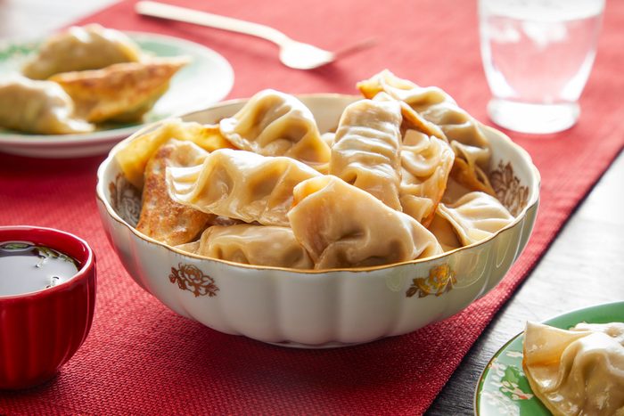 Pork Dumplings in a Japanese Style Bowl and Soy Sauce in a Small Bowl on Red Cloth on Wooden Surface