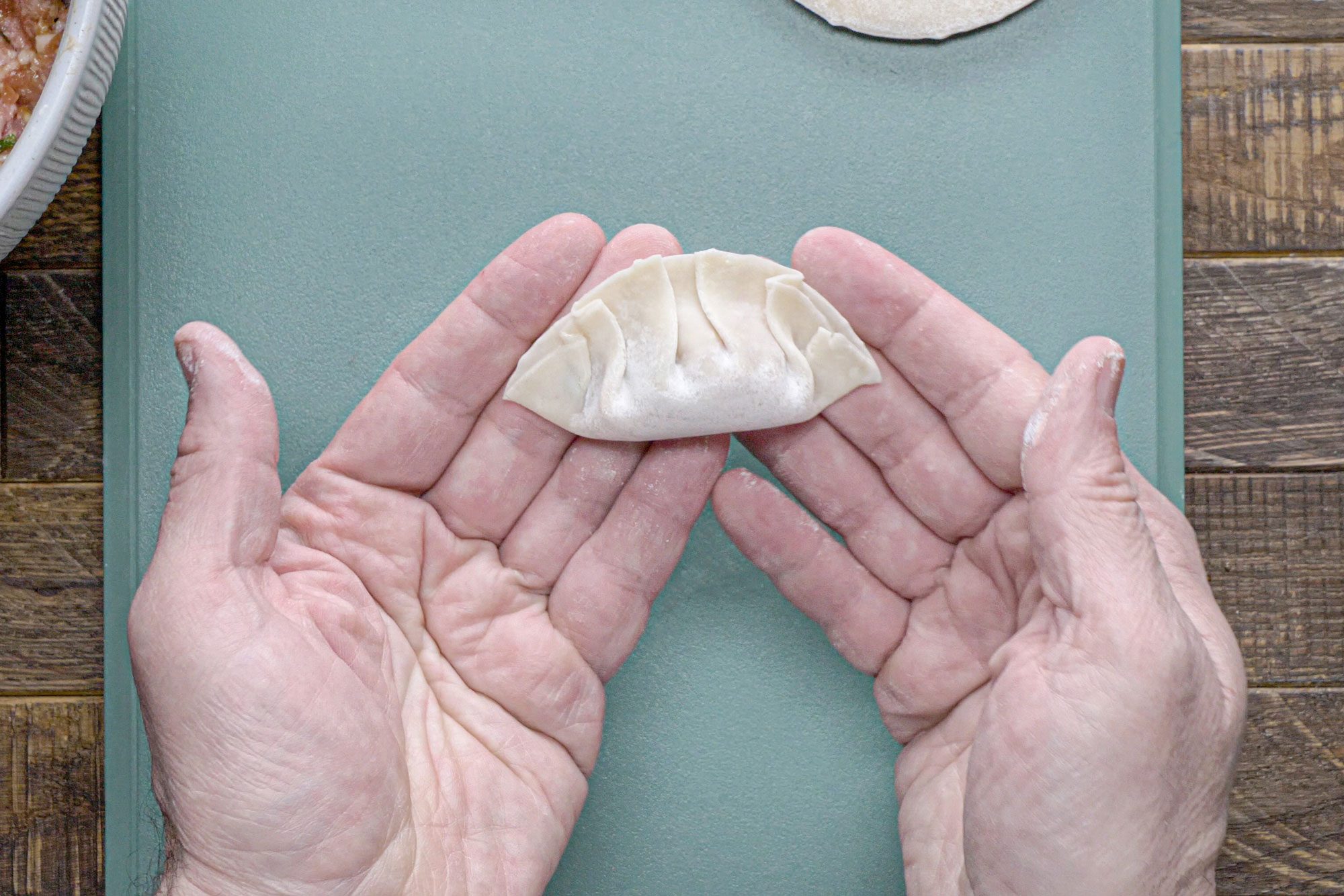 Hands Holding Uncooked Pork Dumpling