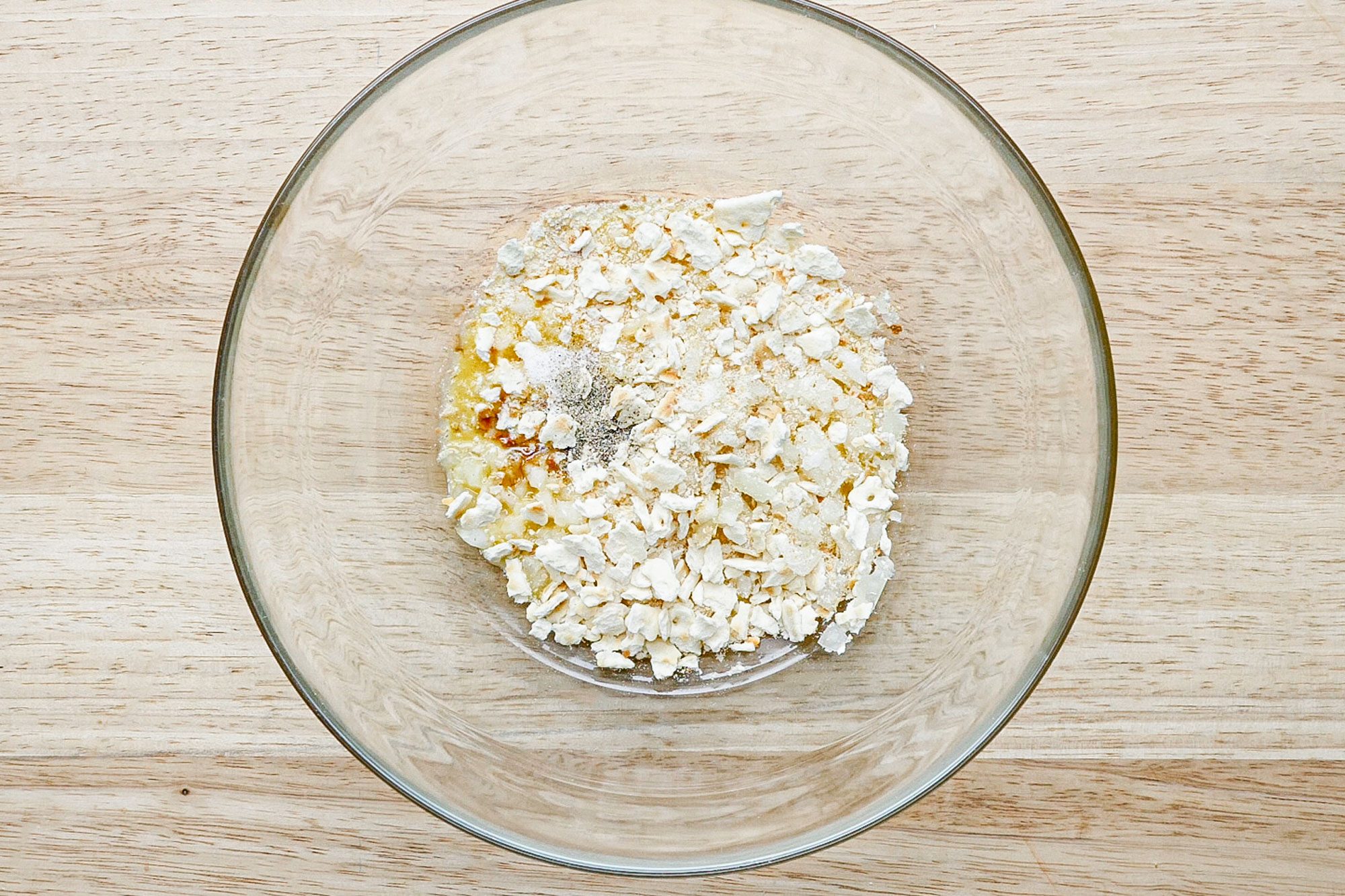 dry ingredients for salmon patties ready to mix in a glass bowl on a wooden surface