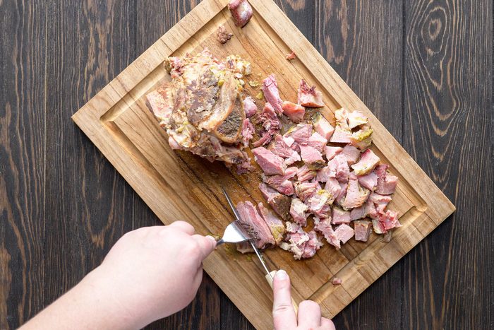 Cutting the meat into small dice on a wooden tray with knife